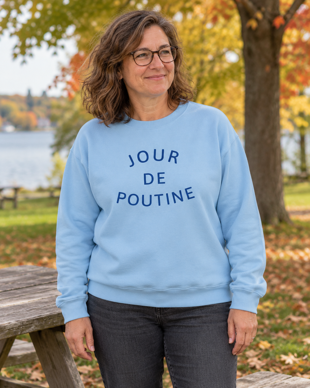 Femme portant le crewneck bleu pâle JOUR DE POUTINE dans un parc.