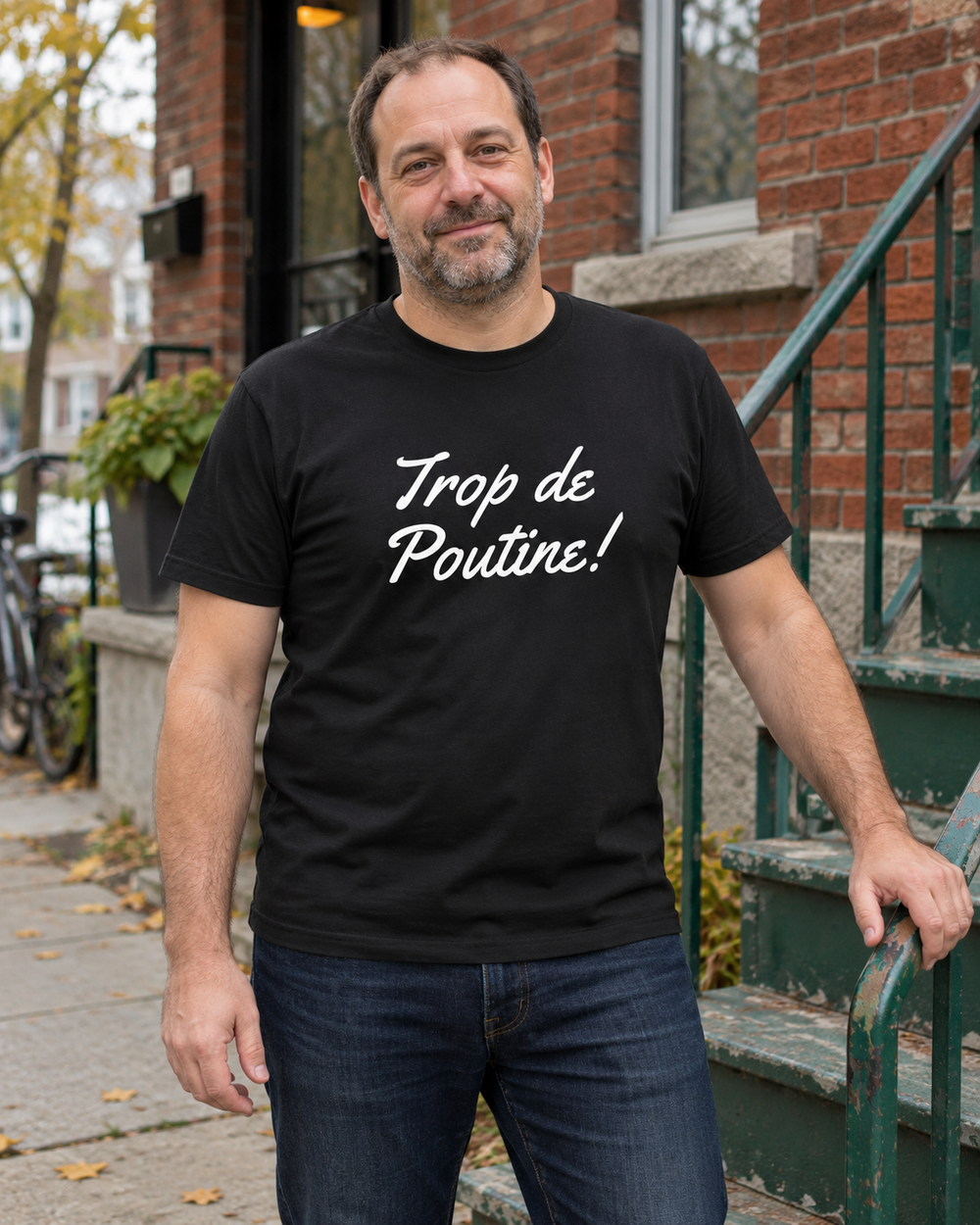 Homme portant le t-shirt noir LE SPORTIF Trop de Poutine devant un duplex.