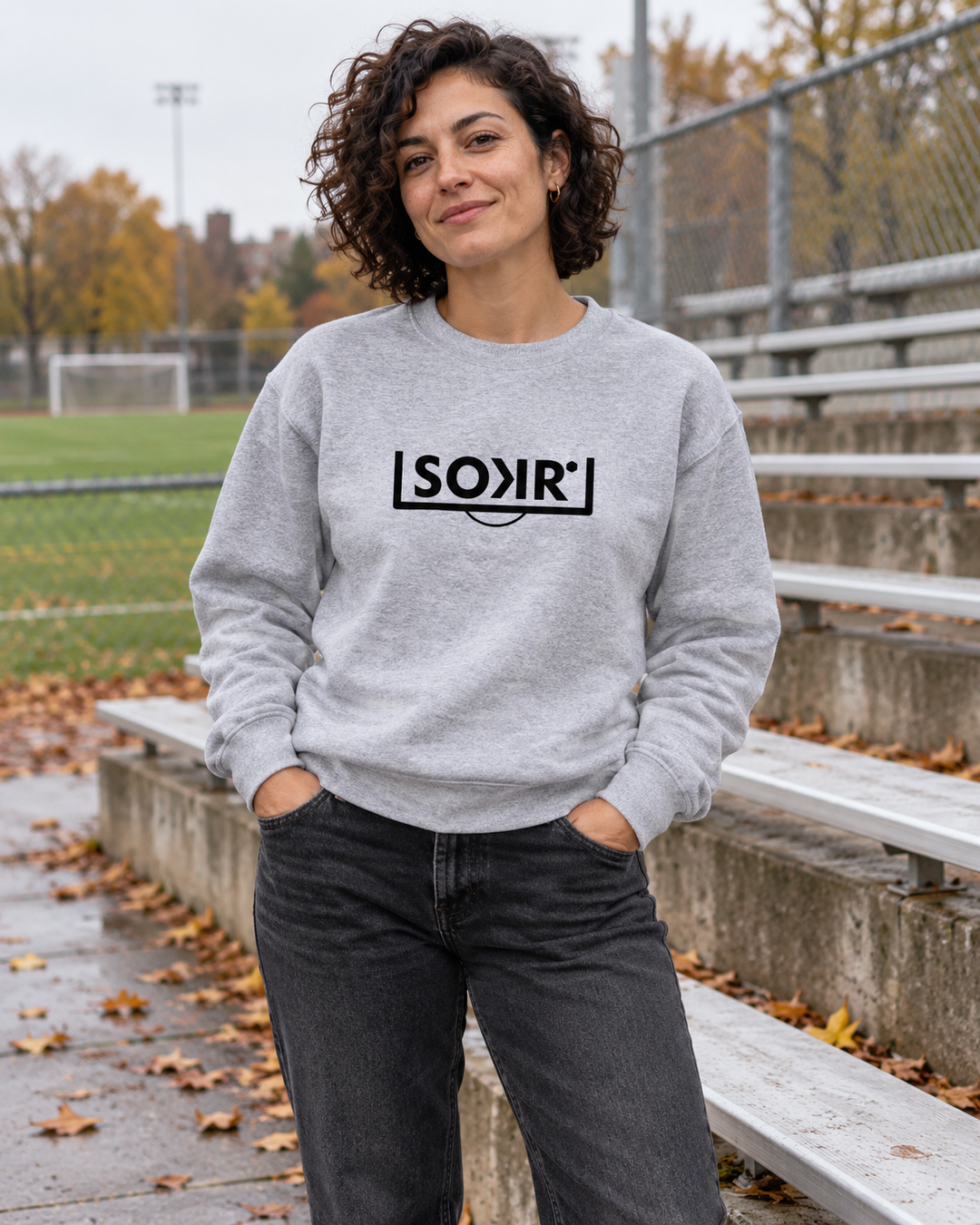 Ouaté SOKR gris chiné à logo noir, porté au bord d’un terrain de soccer.