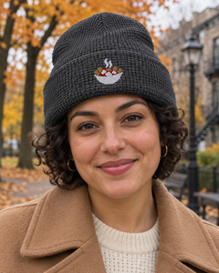 Tuque gaufrée charbon La Sauce chaude, petit motif de poutine brodé, portée avec un manteau.